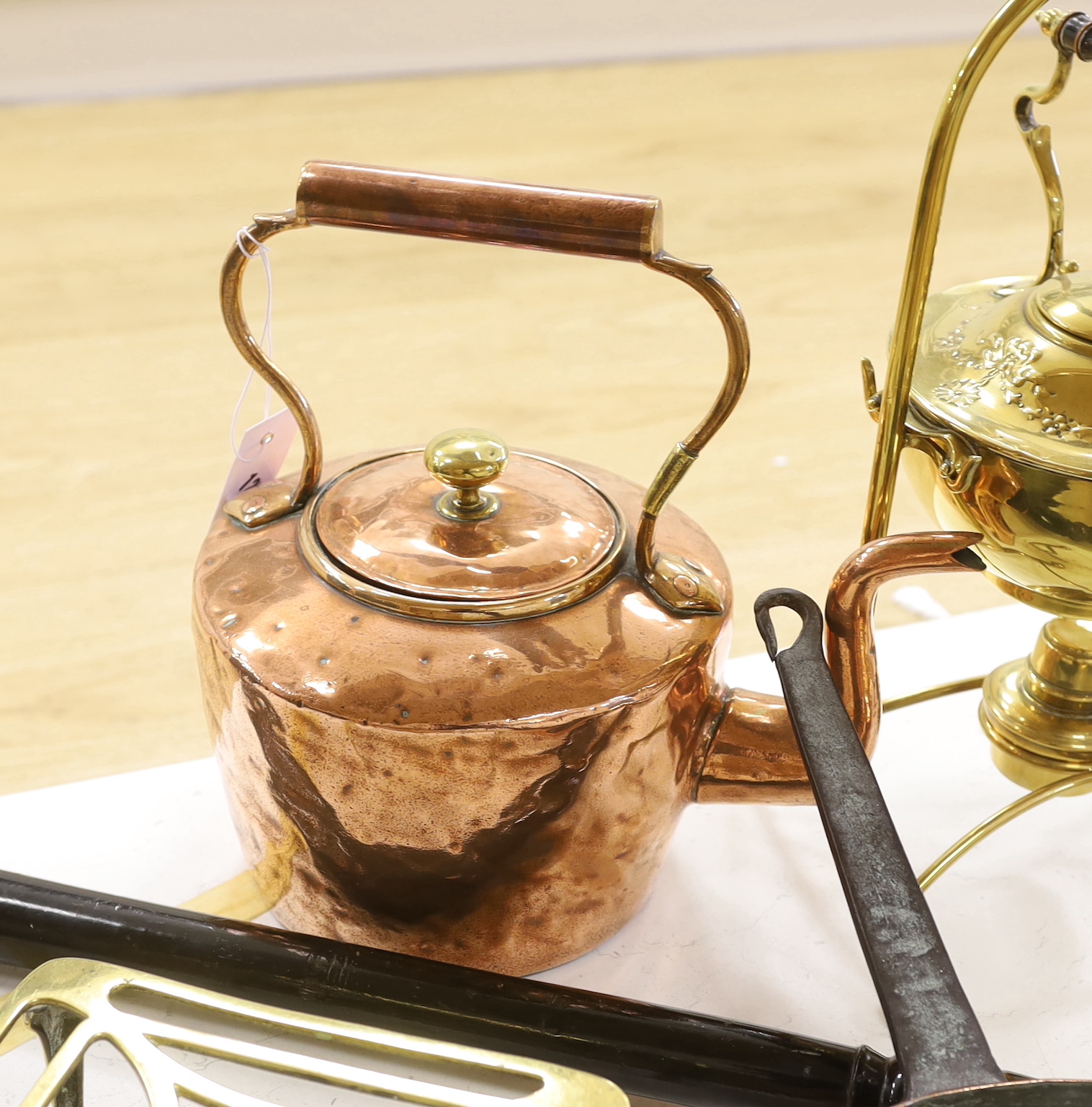 A mixed group of brass / copper wares: copper kettle, a brass spirit kettle, a copper saucepan, a brass trivet and a brass and copper warming pan with ebonies handle, the largest 104cm in length